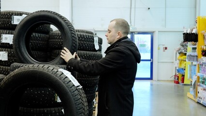 Winter tire specialist choosing studded snow tires, carefully inspecting treads for maximum...