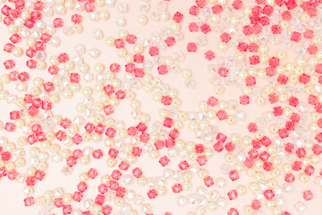 Texture made from different acrylic beads scattered on a pink background.