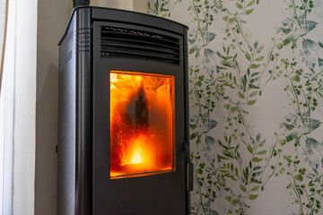 Horizontal photo of a very dirty pellet stove inside a living room of a house. Renewable energy source. Biomass in the form of pellets.