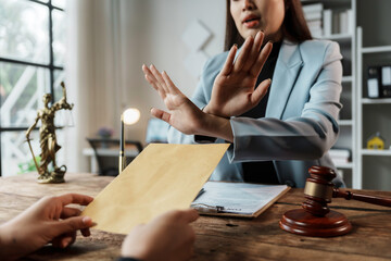 Lawyer showing stop hand gesture, refusing to accept bribe or illegal money inside courtroom with...