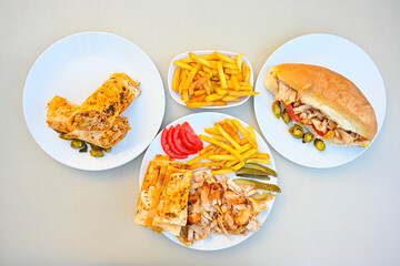 Turkish  Traditional Ramadan doner kebab with tasty tomato sauce and rice or turkish pilav in white plate on table background. Lavash doner kebab ( doner zurna durum )  or shawarma sliced in plate 