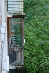 old Soviet balcony, facade of the house is in poor condition. dilapidated neighborhood of abandoned houses among green trees. antique real estate.