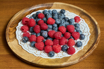 A Beautiful Arrangement of Fresh Berries on a Wooden Plate Raspberries and Blueberries