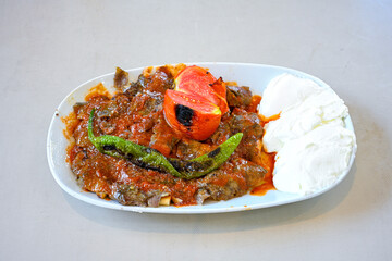 Turkish  Traditional Ramadan doner kebab with tasty tomato sauce and rice or turkish pilav in white plate on table background. Lavash doner kebab ( doner zurna durum )  Pilavustu doner Iskender kebap