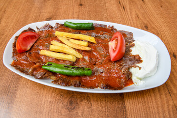 Turkish  Traditional Ramadan doner kebab with tasty tomato sauce and rice or turkish pilav in white plate on table background. Lavash doner kebab ( doner zurna durum )  Pilavustu doner Iskender kebap