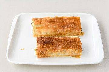 Turkish style meat stuffed filo dough borek served kol boregi.Cheese and minced pie are sliced on a marble background. Turkish name: Kol Boregi, kiymali, peynirli su boregi. Ci borek. Kafkas cig borek