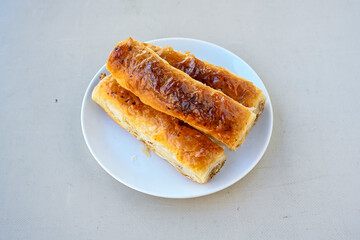 Turkish style meat stuffed filo dough borek served kol boregi.Cheese and minced pie are sliced on a marble background. Turkish name: Kol Boregi, kiymali, peynirli su boregi. Ci borek. Kafkas cig borek