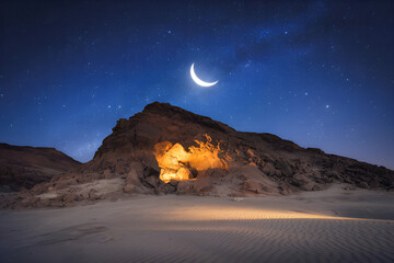 A photo of a calm, moonlit mountain scene with the Cave of Hira glowing softly from within
