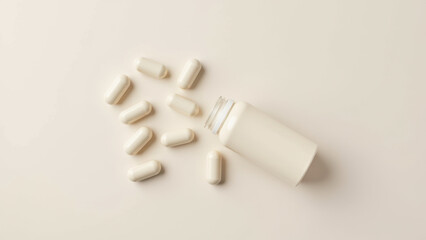 Naklejka premium Magnesium glycinate capsules spilled out of a bottle on a light-colored surface.