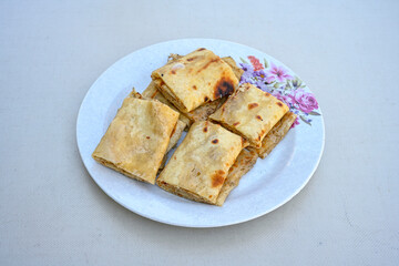 Turkish style meat stuffed filo dough borek served kol boregi.Cheese and minced pie are sliced on a marble background. Turkish name: Kol Boregi, kiymali, peynirli su boregi. Ci borek. Kafkas cig borek