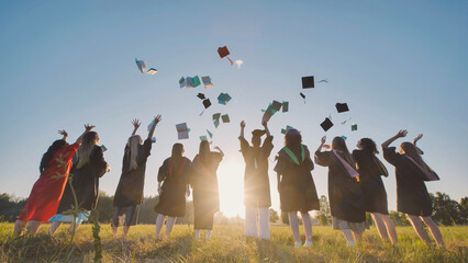 Graduates tossing caps and books in the air at sunset to celebrate their graduation