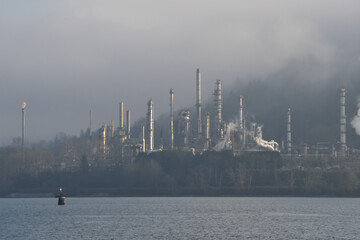 Refinery on the ocean shore in the distance with clouds and fog.