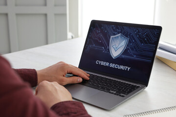 Cyber security. Man using laptop at table, closeup