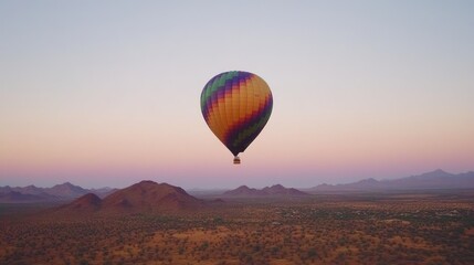 Fototapeta premium Colorful hot air balloon floats over a vast desert landscape at dawn.
