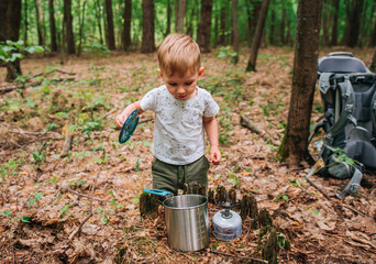 little boy on a hike in the forest prepares food, plays