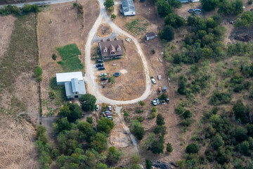 Mustang Ridge, Texas - Aerial view of a ranch outside of Austin Texas in the Hill Country with a farm, trampoline and abandoned cars in the backyard