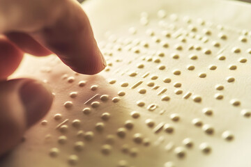 Hands reading Braille text. Horizontal photo. Close-up of hands reading Braille text on a green surface, symbolizing literacy and accessibility for the visually impaired.