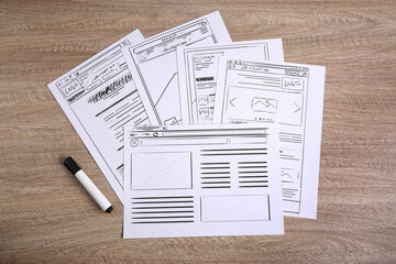 Developing UI design. Sketches of website wireframes and felt pen on wooden table, top view