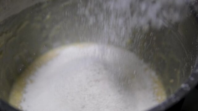 Process of sifting Flour for making Dough in Bakery. Measured Amount of Flour being poured into Large Mixing Bowl through Electrical Sifter Machine. Concept of making Bread