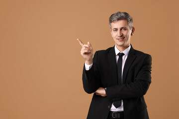 Portrait of businessman on brown background, space for text