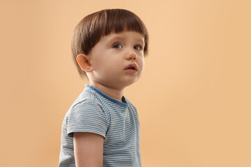 Portrait of cute little boy on beige background. Space for text