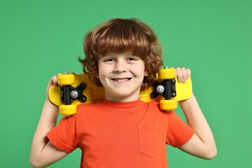 Little boy with penny board on light green background