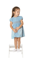 Little girl standing on step stool against white background