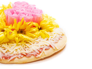 Pink roses in heart love shape and white chamomile flowers on top of a pizza and on white background. Abstract conceptual art. Selective focus.