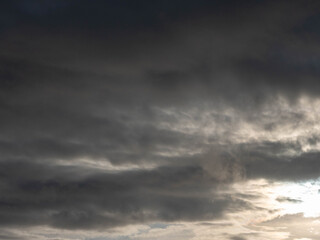 The sky is filled with fluffy clouds, and the sun is peeking through them, creating a beautiful and calming scene. The clouds are scattered throughout the sky, with some closer to the horizon