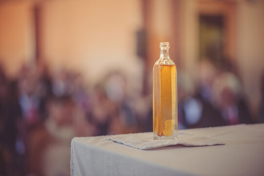 Close-up of a Bottle of holy oil (chrism) for a baptism on a church altar with the congregation in the background