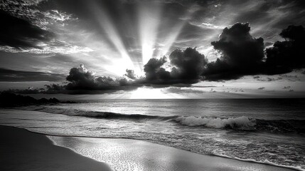 Dramatic black and white beach sunset with sun rays breaking through clouds.