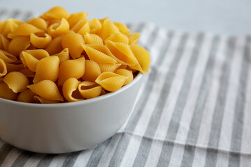 Dry Organic Medium Pasta Shells in a Bowl, side view. Copy space.