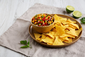 Homemade Corn Salsa with Tortilla Chips on a Plate, side view. Copy space.