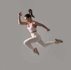 Woman in gym clothes doing exercise on grey background