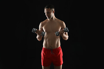 Man exercising with dumbbells on black background