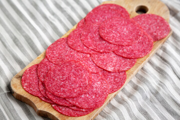 Sliced Spanish Salami Extra on a wooden board, side view.