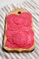 Sliced Spanish Salami Extra on a wooden board, side view.