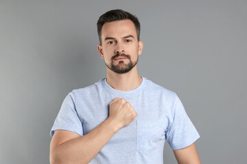 Man making promise on grey background. Oath gesture