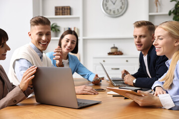 Group of people using different gadgets at wooden table in office. Modern technology