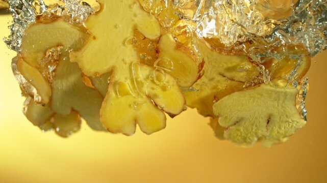 Super Slow Motion of Falling Ginger Pieces into Water. Isolated on Colored Background. Filmed on High Speed Cinema Camera, 1000 fps.