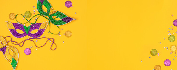 Top view of a beautiful composition of colorful masks, confetti, Mardi Gras decorations. Yellow Mardi Gras banner. Mardi gras holiday background © prime1001