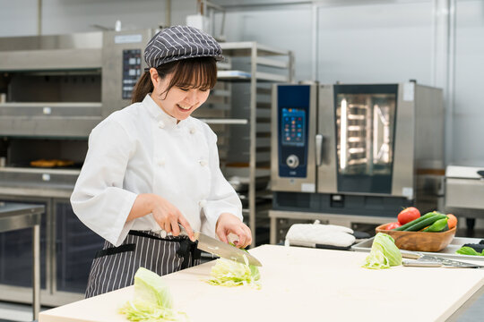厨房でキャベツを切る調理スタッフの女性
- Powered by Adobe