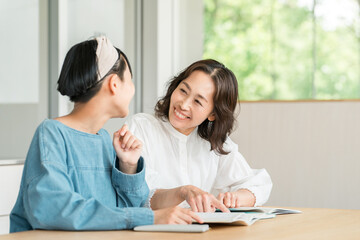 小学生・中学生の女の子に笑顔で勉強を教える母親・教師・塾講師・家庭教師の女性
