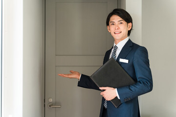 モデルハウス・モデルルームを案内するハウスメーカーのアドバイザー・プランナーの男性
