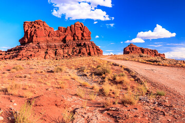 A desert landscape with a dirt road leading to a large rock formation