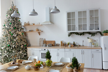 There is a Christmas tree in the corner of the kitchen. A set festive table for the whole family.