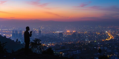 Silhouette of Man Praying at Dawn Over a Cityscape