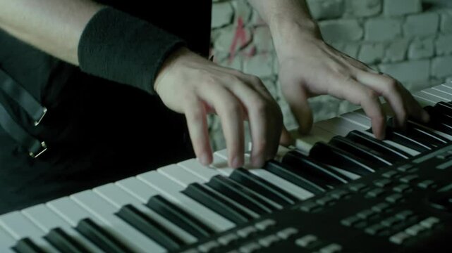 Close up of male hands skillfully playing a synthesizer keyboard in a vibrant recording studio, passionately crafting electronic music and composing captivating melodies