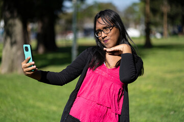 Latin transgender woman taking a selfie in the park