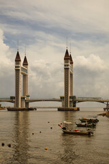 A stunning photogenic drawbridge in Kuala Terengganu, Malaysia, under a dramatic cloudy sky. The...